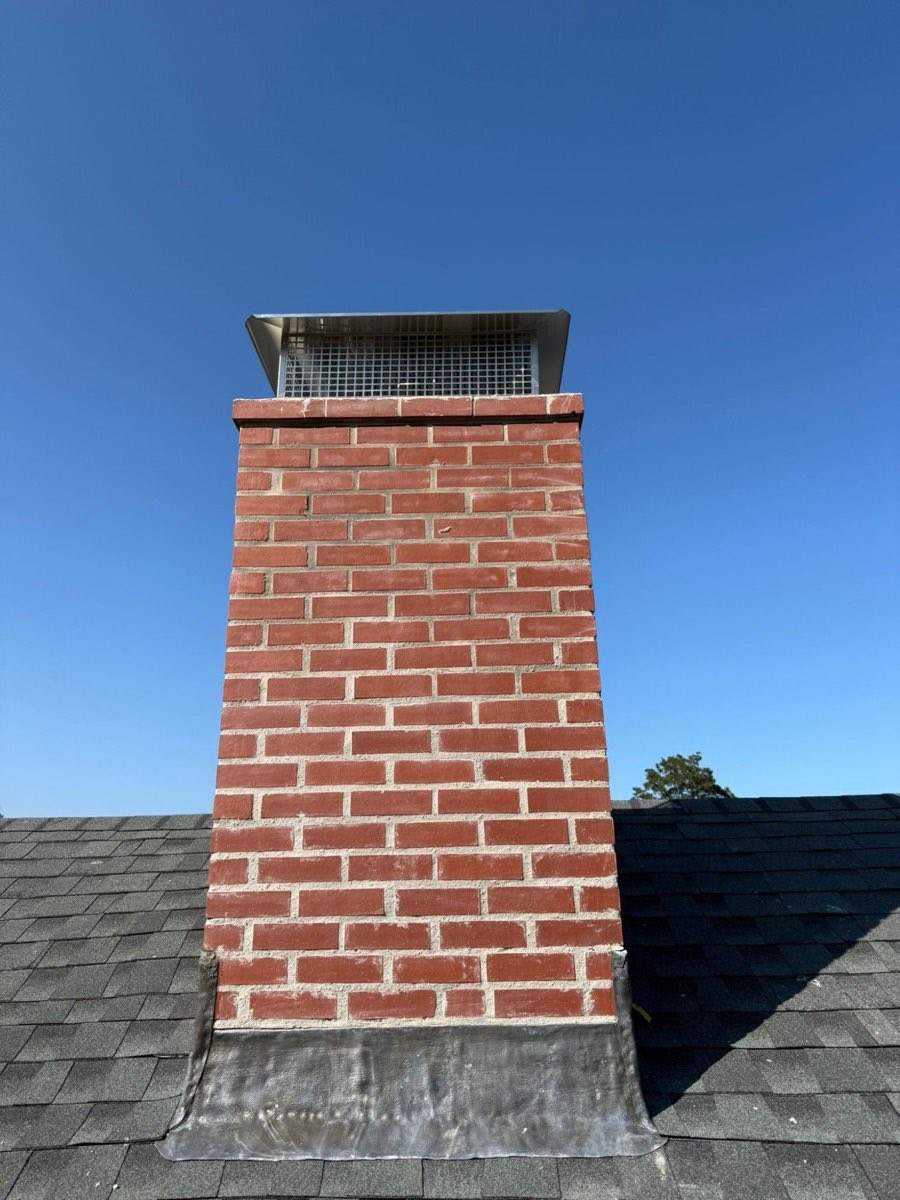 Completed brick chimney rebuild with new stainless steel chimney cap in Dedham, MA