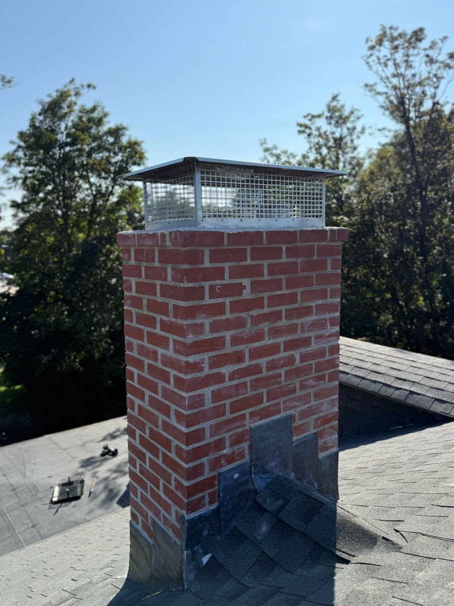 Repointed brick chimney with stainless steel cap and fresh lead flashing in Dedham, MA
