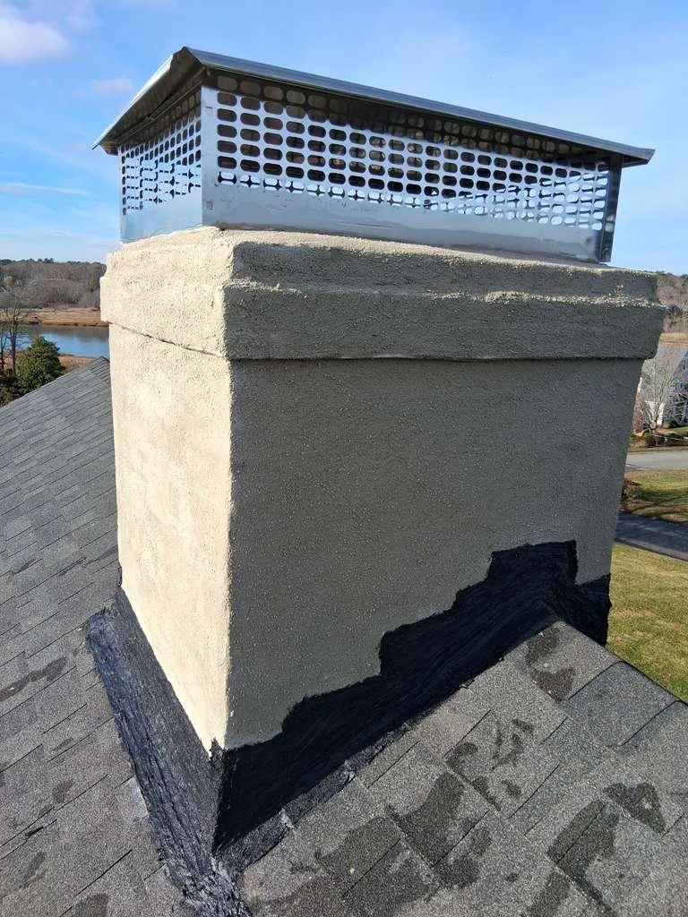 Parged chimney crown with a new stainless steel chase cover overlooking a coastal marsh