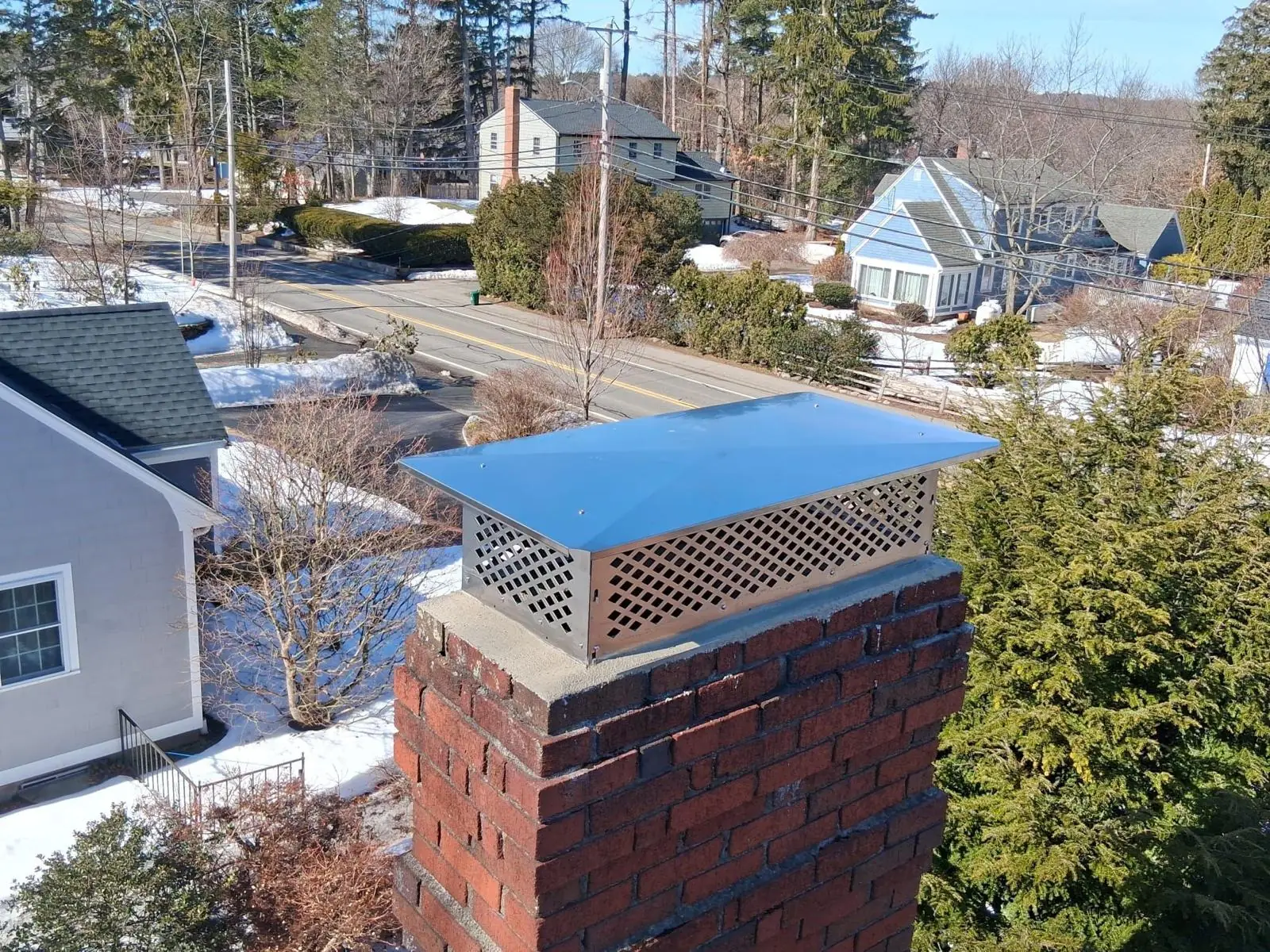 Black multi-flue chimney cap on a brick chimney in winter in the South Shore