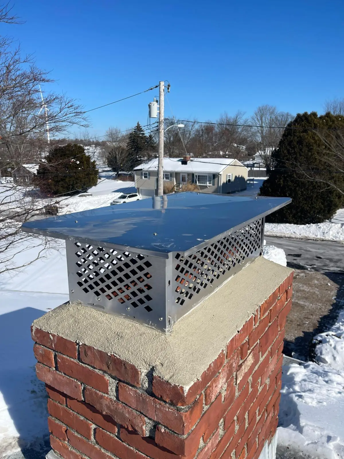 Stainless steel multi-flue chimney cap installed on a brick chimney