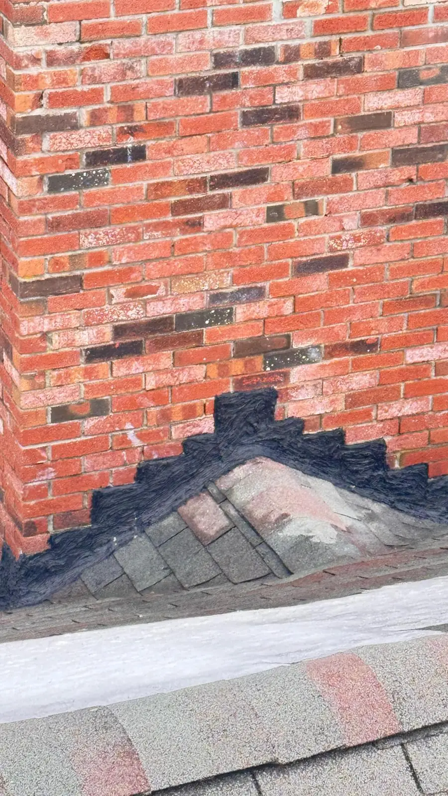Close-up of chimney flashing sealed where the chimney meets the roof