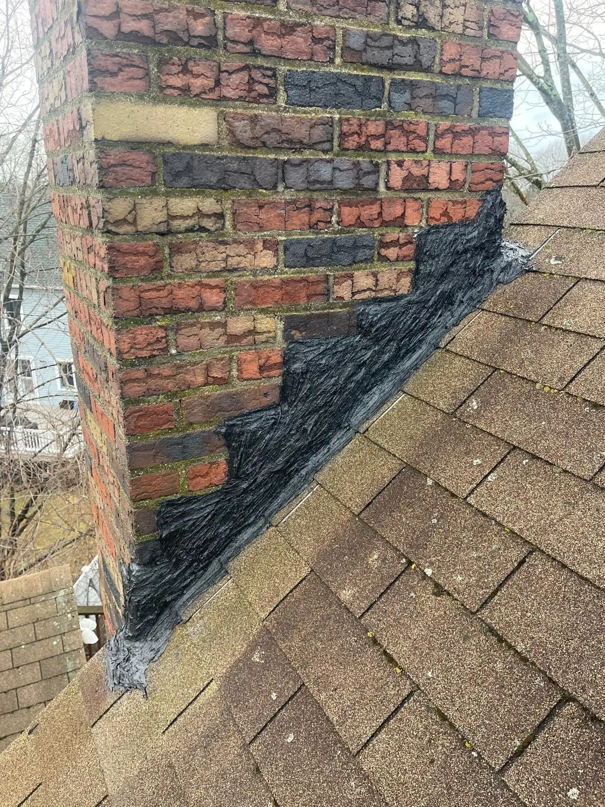 Chimney flashing repair at the base of a brick chimney in the South Shore