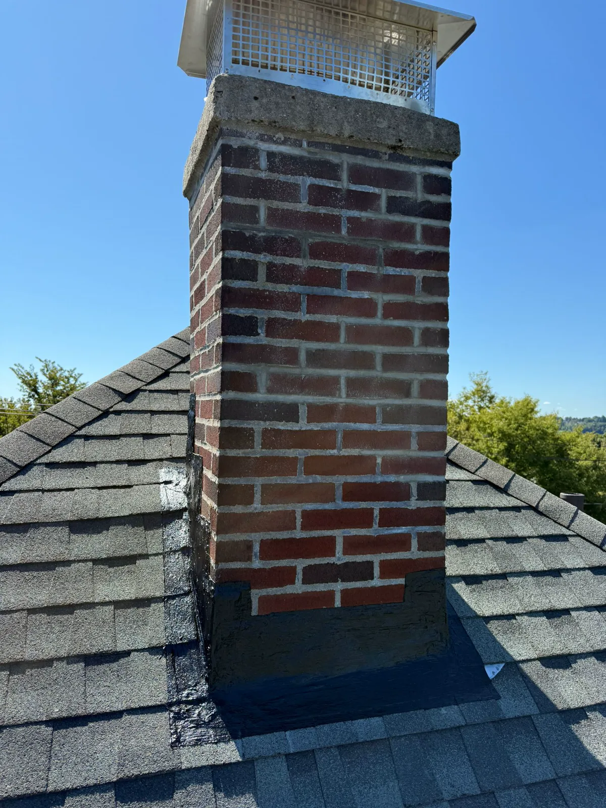 Repaired brick chimney with a stainless cap and fresh flashing seal